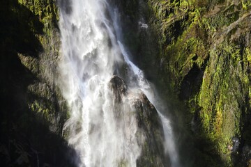 Fototapeta premium Stunning view of a waterfall cascading down a mountain cliff in Fjordland South Island, New Zealand.