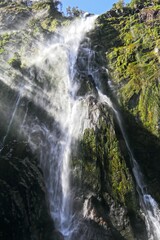 Stunning view of a waterfall cascading down a mountain cliff in Fjordland South Island, New Zealand.