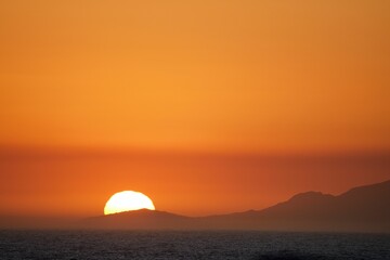 Fototapeta premium Mountains silhouetted against the vibrant sky at sunset. Simon's Town, Western Cape.