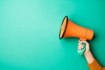 Hand holding megaphone on blue background with copy space.