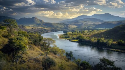 A serene and picturesque view of a meandering river flowing through a lush landscape with majestic mountains in the background