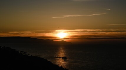 Obraz premium Majestic orange sunset illuminates the horizon over the distant ocean.