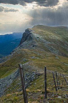 Wooden fence on a mountain peak with a dramatic sky of rolling clouds in the background