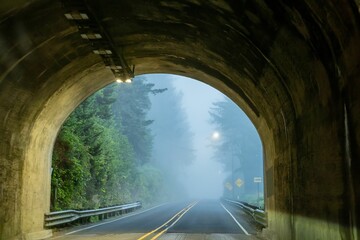 Scenic view of a winding road passing through a tunnel with misty trees in the background