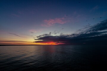 the sun is setting in the blue water at dusk over the ocean