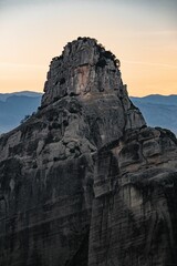 Vertical shot of a rock formation with a majestic sunset in Meteora, Greece.