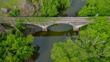 Fototapeta premium Aerial shot of an abandoned railway bridge in a lush, wooded area in Eastern Kentucky.