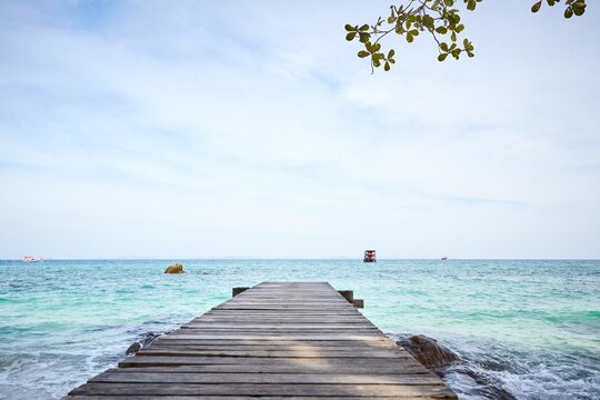 Tranquil view of a wooden walkway leading into the crystal clear tropical waters in Thailand