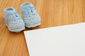 Blue baby booties on a wood desk with blank paper - 771516415