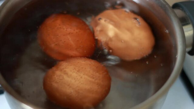 Close-up eggs are boiled in a metal pan. Chicken eggs are boiled in boiling water in a saucepan