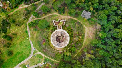 Majestic top view of a monument standing tall in a lush forest, surrounded by a variety of trees