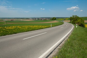 the roadway passes by farm land and farmland with white lines