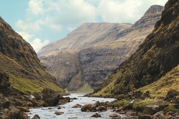 Picturesque mountain stream flowing between large rocks and lush green mountains.