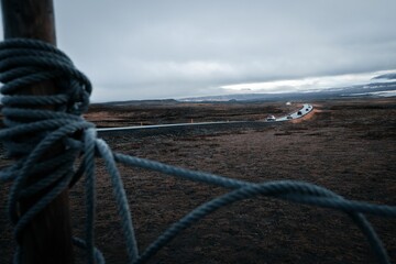 A street in Iceland between brown grasslands with ropes and cars.