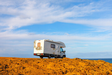 Camper car on the rocky coast of the ocean. Camper van parked along the rugged shoreline 