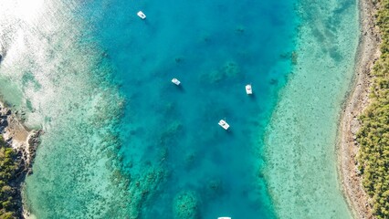Aerial view of several boats peacefully floating in the pristine ocean water.