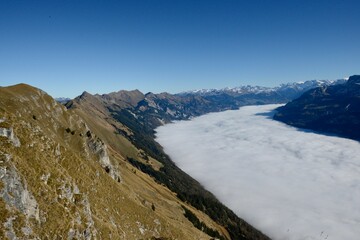 Wispy clouds cascading down the rugged slopes of a mountain range at Bernese Highlands