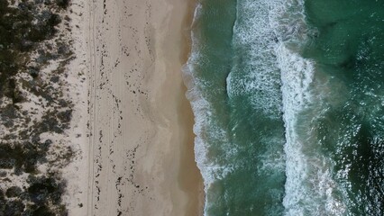 Aerial view of a sandy beach with soft ocean waves