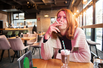A woman smokes a cigar, drinks hot chocolate in a cafe and enjoys her free time