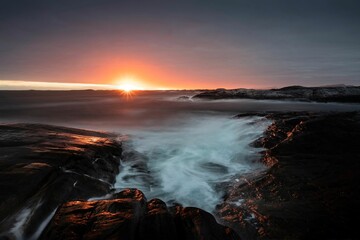 Golden sunset sky stretches across the horizon, illuminating the ocean. Norway, Atlantic Ocean Road.