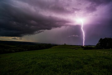 a purple lightning bolt in the night sky on a cloudy day