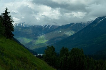 a scenic mountain valley and snow covered mountains with evergreen trees
