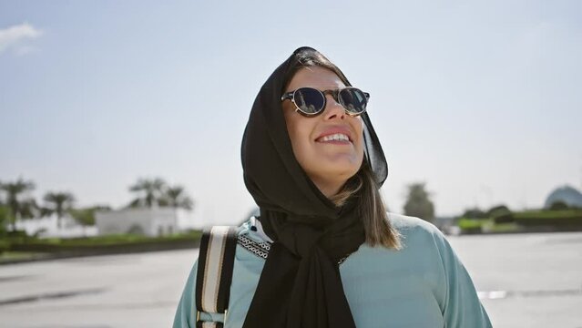 A smiling woman in hijab with sunglasses at an islamic mosque in abu dhabi