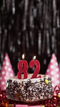 Number eighty-two birthday candle on sweet cake on dark background, 82nd birthday. Blow out the holiday candle.