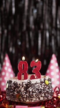 Number eighty-three birthday candle on sweet cake on dark background, 83rd birthday. Blow out the holiday candle.