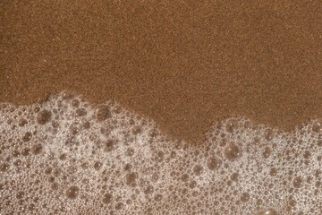 High-resolution closeup shot of waves crashing onto a white sandy beach