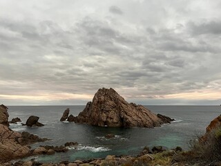 a cloudy sky at an ocean cove, with many boulders in the water