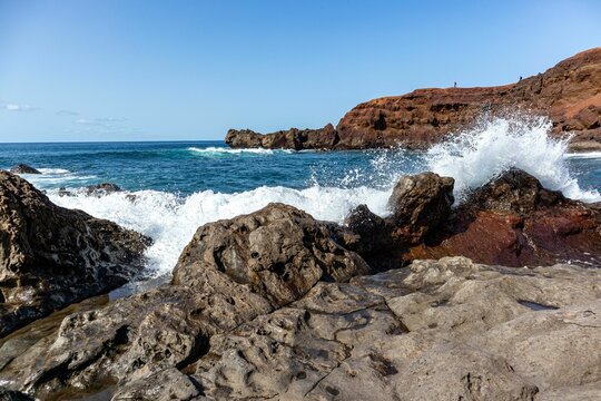 Picturesque beach scene featuring crashing waves on a rocky shoreline.