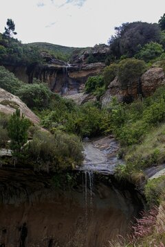 Cascading waterfall surrounded by lush, green vegetation and foliage in Clarens, Free State