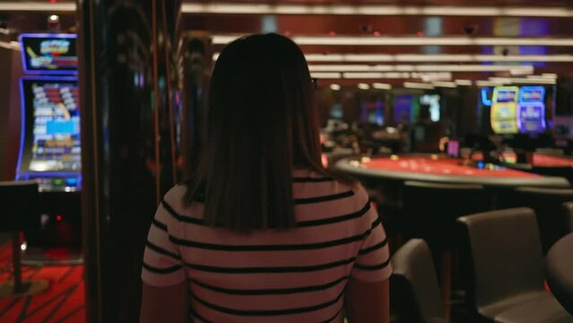 Brunette woman standing in a casino with blurred slot machines and poker tables, conveying an ambiance of entertainment and risk.