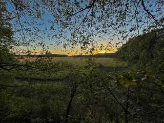 Scenic view of a green field at cloudy sunset