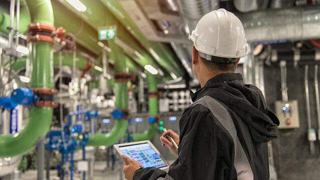 workers in factory.  workers at work. People in Industrial interior chiller and boiler HVAC heating ventilation air conditioning system.