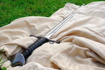 A metal sword lies on a white cloth on the grass
