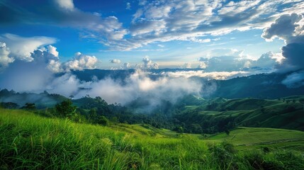 Green grass field on slope with blue sky and clouds background, cloud mountain tropic valley landscape, wide misty panorama