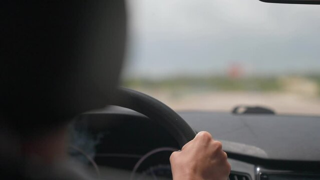Close up slow motion view from back seat of driver smoking cigarette inside a car. Most common traffic violation 