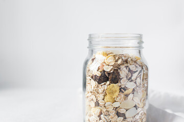 oat muesli in a glass jar, muesli with oats almonds raisins and cornflakes in a glass jar, prepping...