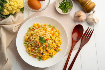 Cauliflower fried rice,Stir fried cauliflower rice with eggs ,carrot ,bean and corn in white plate.healthy eating and low calories food.low carb dish.Top view