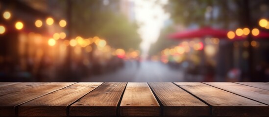 An empty hardwood table sits against a backdrop of a blurred city street. The warmth of the wood...