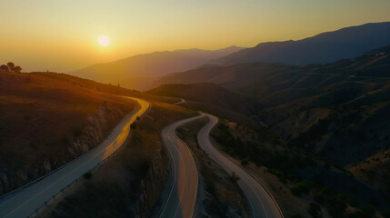 A beautiful aerial view of the curvey road at sunset surrounded by mountain