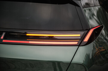 Right turn indicator signal. Red tail lights closeup. Modern concept supercar exterior design detail, headlight. Back view. Right rear light shining on new modern electric sedan car. Concept of future - obrazy, fototapety, plakaty