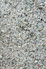 Many small pieces of broken shattered glass of different colors, top view. Abstract texture gray vertical wallpaper. Abandoned Glass factory. 