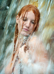 beautiful young cute sexy Portrait of a nude redhead woman under the splashing pattering waterfall burbling water
