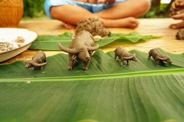 Take clay and make large and small buffalo shapes and place them on banana leaves. Children's free...