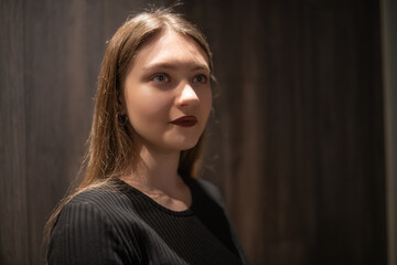 Portrait of a young beautiful long-haired girl in dark clothes in a low key.