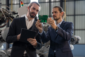 Two professionals in suits engaged in a discussion and held circuit board for production of robot...