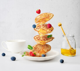 Flying pancakes and berries topped with honey, pancake levitation,